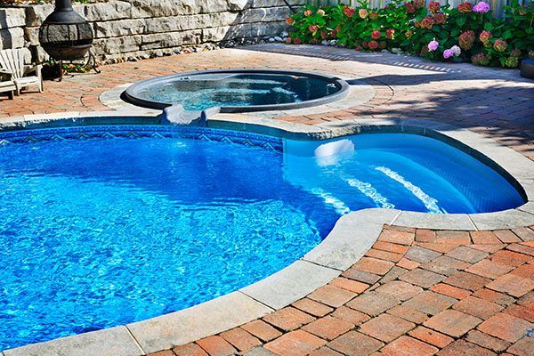 Outdoor inground residential swimming pool in backyard with hot tub