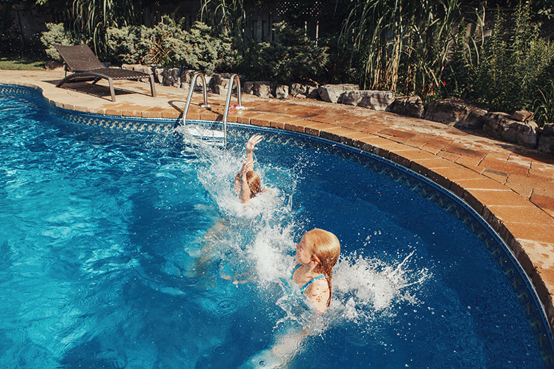 Girls swimming in a backyard pool.